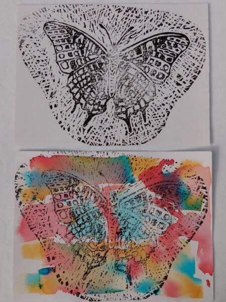 Two test lino prints of butterflies in black ink one with a multicoloured blended background in watercolours the other plain